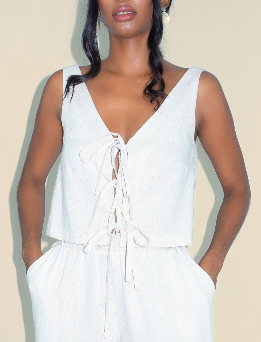 Woman wearing a white sleeveless jumpsuit on a plain background