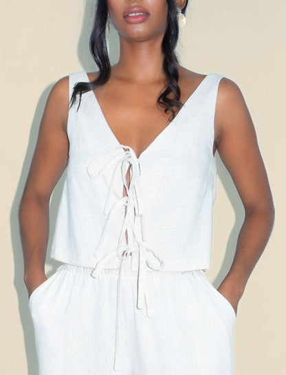 Woman wearing a white sleeveless jumpsuit on a plain background