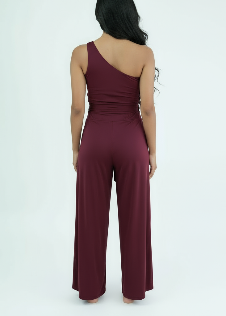 Woman wearing a burgundy one-shoulder jumpsuit on a white background