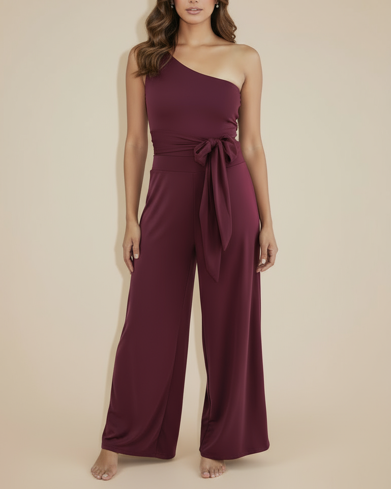 Woman wearing a burgundy one-shoulder jumpsuit on a beige background By Ana Del Pozo 