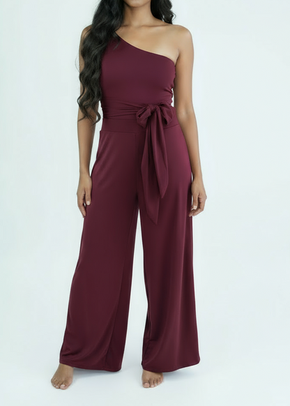 Woman wearing a burgundy one-shoulder swimsuit and flare pants suit on a white background