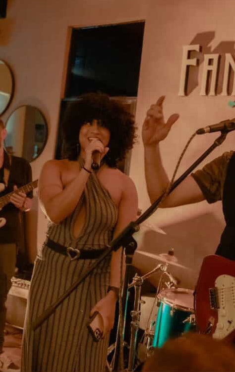 Band performing on stage with a text overlay 'Amo ese vestido' on a brown background